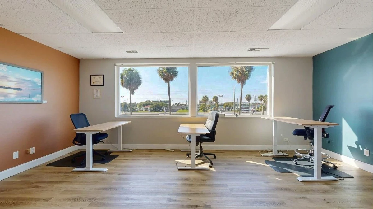 Social seating room with sit-stand desks and palm tree views